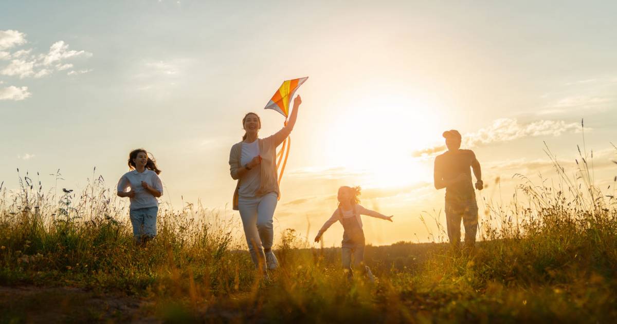 Vrolijke familie met een vlieger bij een ondergaande zon